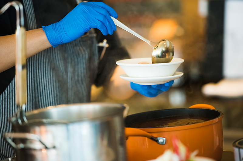 Person ladling soup in a soup kitchen