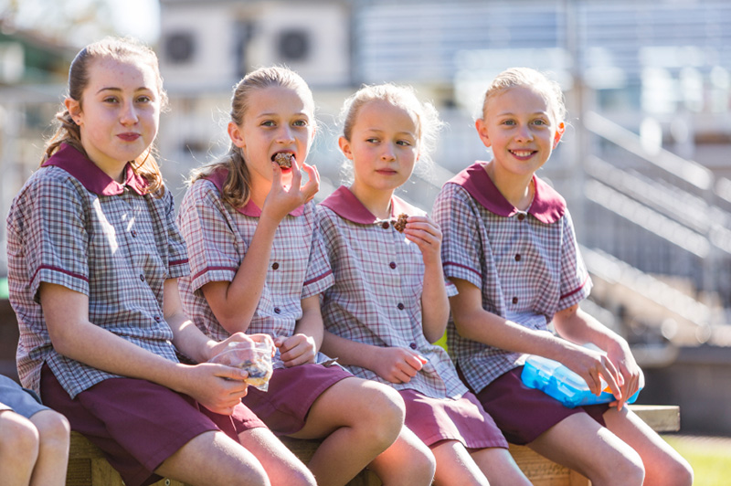 Four schoolgirls sitting and eating lunch.