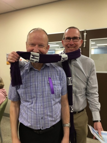 Two men wearing a football scarf.
